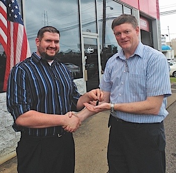 Seller C.J. Passmore II (left) passes the business keys to new owner Bill Brickhill.